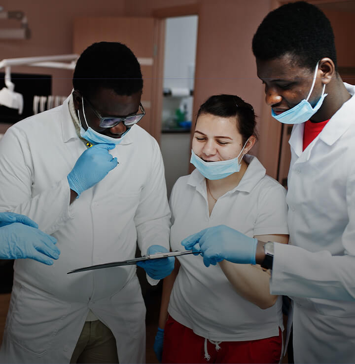 Equipo de 3 profesionales de la odontología con batas blancas mirando el historial de un paciente Equipo de 3 profesionales de la odontología con batas blancas mirando el historial de un paciente