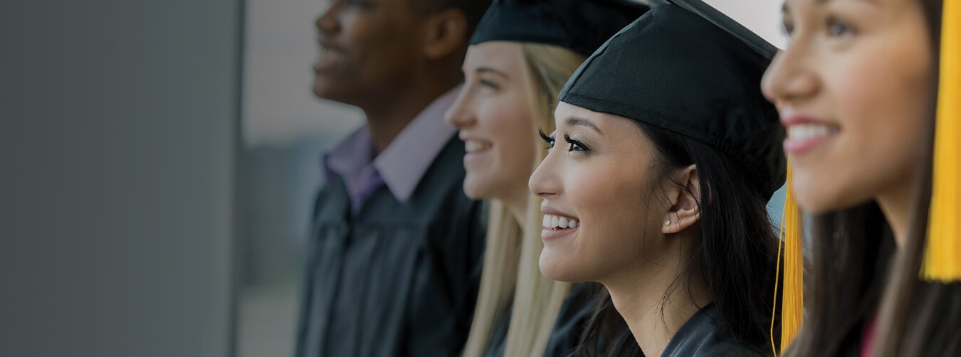 estudiantes sonriendo mientras usan togas y birretes negros en una ceremonia de graduación